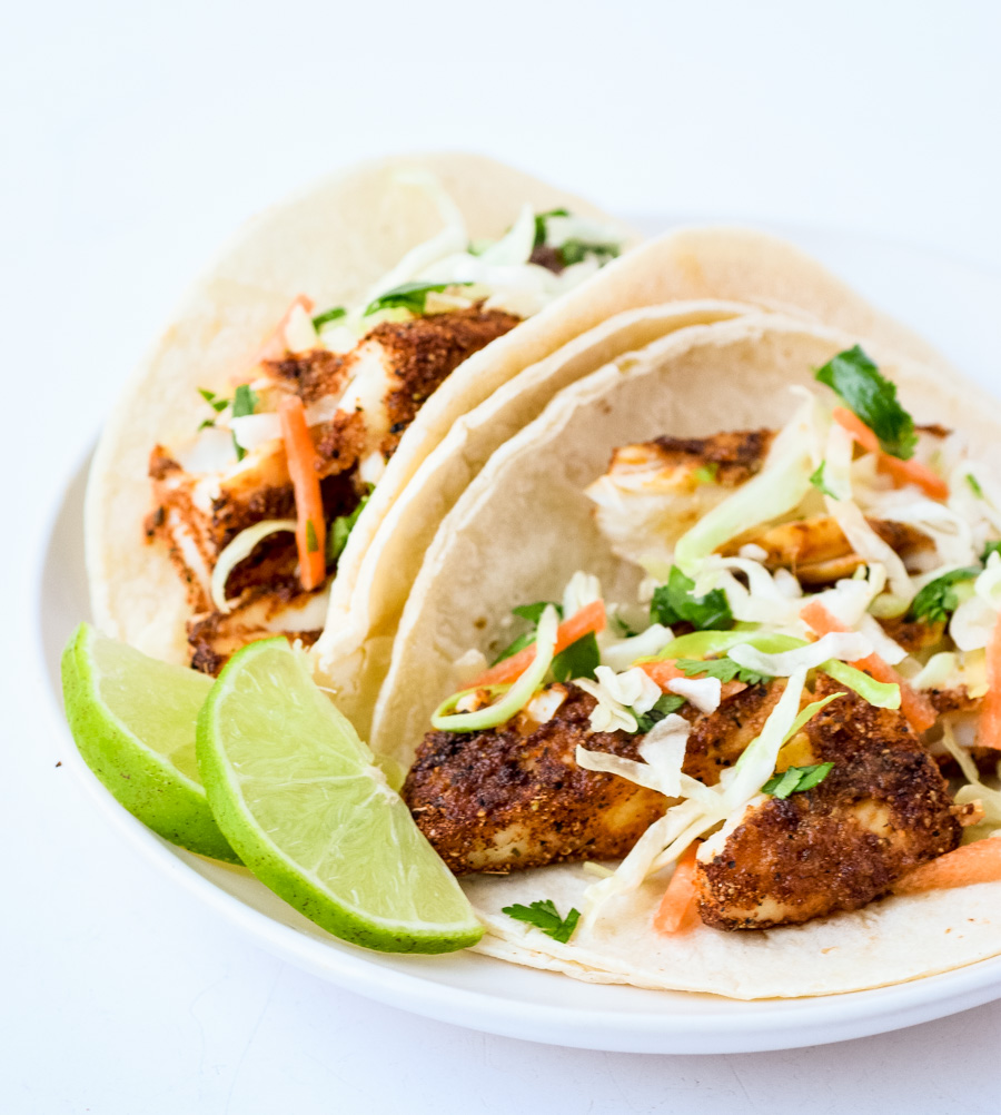blackened fish tacos in tortillas with lime wedges