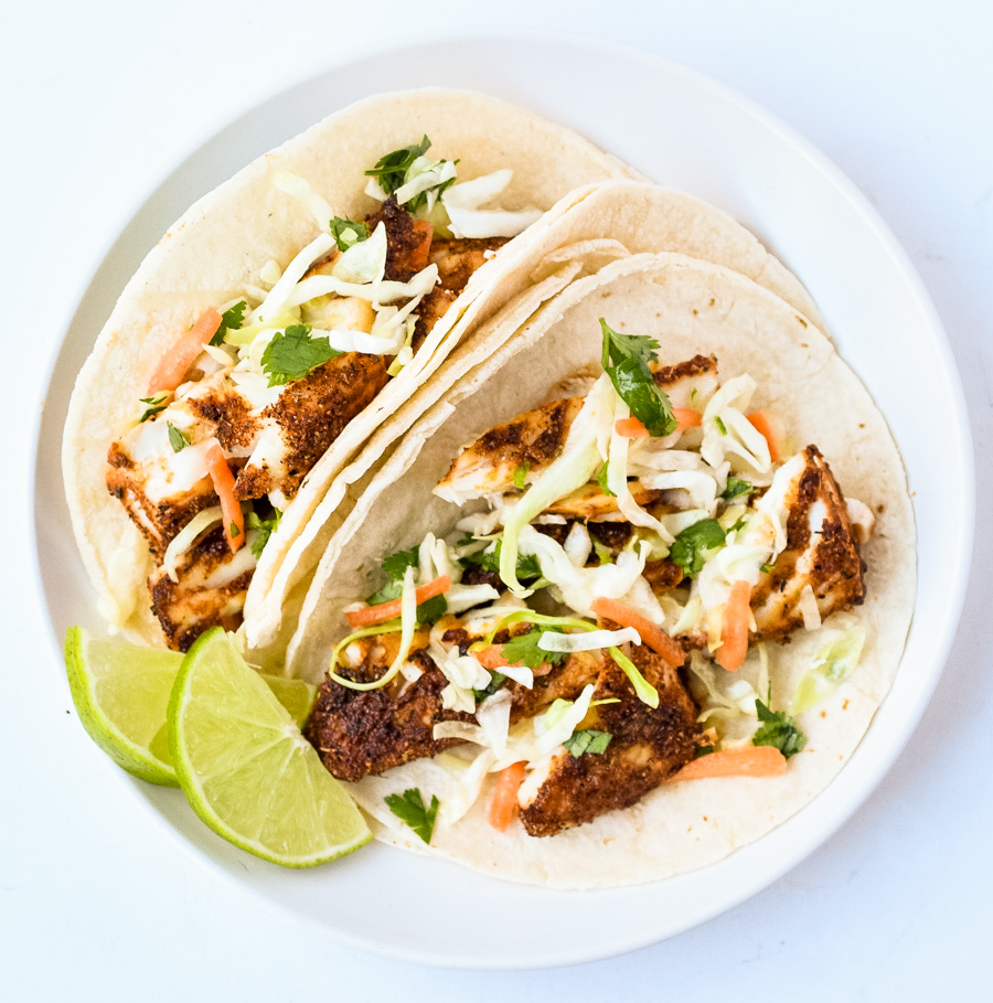 blackened fish tacos in tortillas with lime wedges