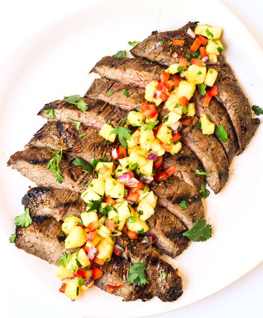 sliced grilled flank steak topped with pineapple salsa