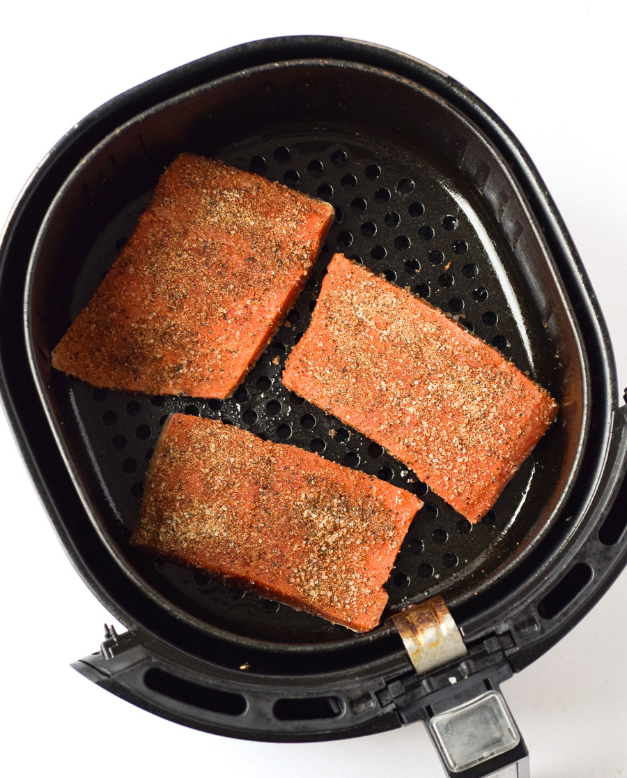 raw salmon filets with blackened seasoning in air fryer basket