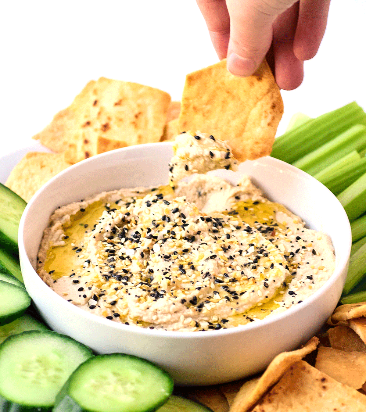 bowl of homemade hummus topped with everything bagel seasoning scooped on a pita chip