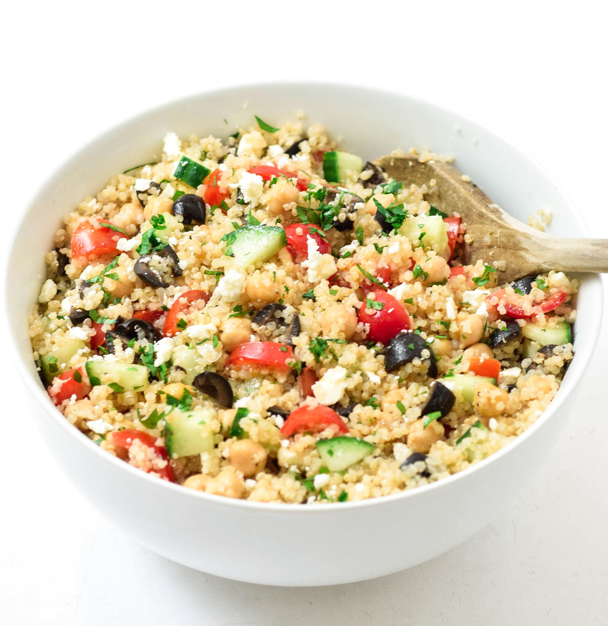 close up of Greek quinoa salad with chickpeas and large wooden spoon