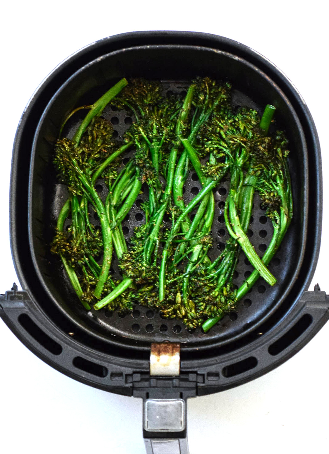 cooked broccolini arranged in air fryer basket