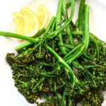 air fried broccolini on a plate with lemon slices